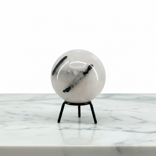 A Quartz Tourmaline Sphere with black inclusions, displayed on a small black metal stand on a white marble surface against a white background.