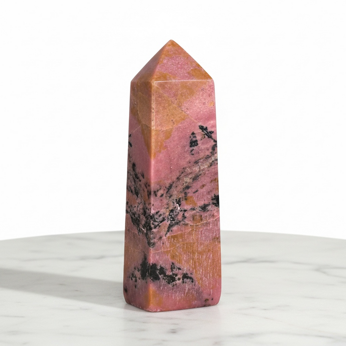 Kindred Crystal Collective — Rhodonite Obelisk, polished rose-pink and peach rhodonite obelisk with bold black manganese veining, white background