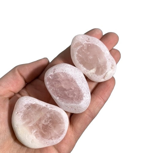 Kindred Crystal Collective — Rose Quartz Ema Eggs 4–5cm, three naturally tumbled river stones held in hand showing frosted white exterior and flat polished window revealing pale blush pink rose quartz interior