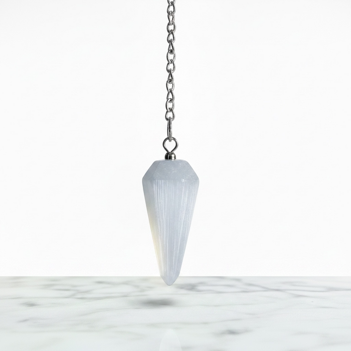 Selenite Pendulum with Chakra Beads on white background — translucent white selenite with colourful chakra beads