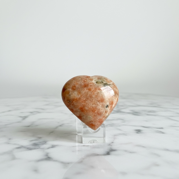 Natural sunstone carved crystal heart in warm reddish-orange with glittering aventurescence, for vitality, sacral chakra and good fortune