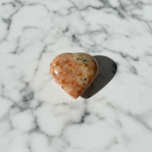 Sunstone crystal heart close-up showing warm orange tones and natural sparkle, a healing crystal for joy, confidence and life-force energy