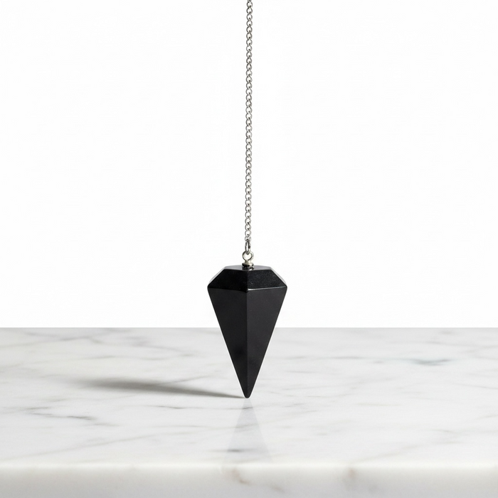 Shungite crystal pendulum close-up showing deep matte black carbon surface, used for energy healing and balance