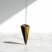 Tigers Eye Gold Pendulum crystal on white background — golden brown chatoyant stone