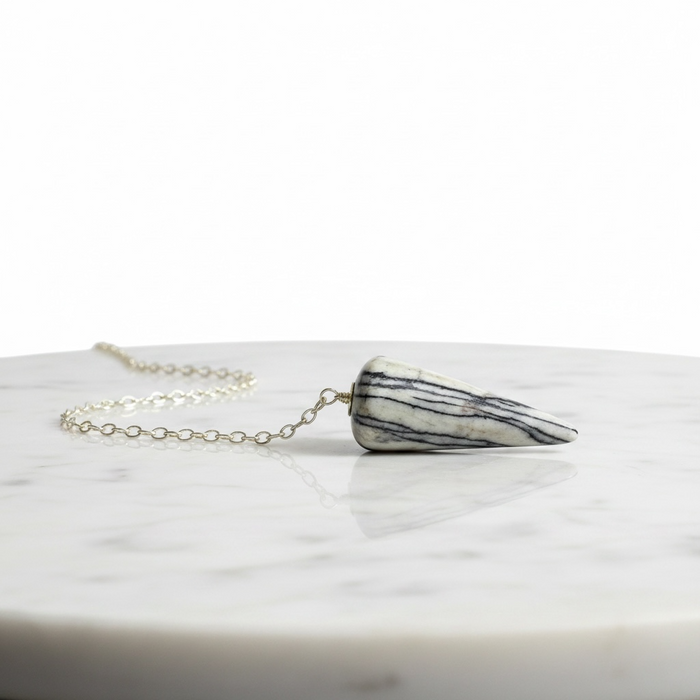 Zebra Jasper Pendulum crystal on white background  distinctive black and white striped pattern