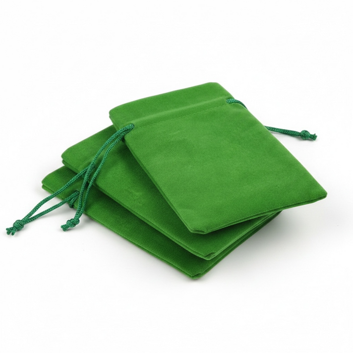 Stack of grass green velvet drawstring bags on a white background