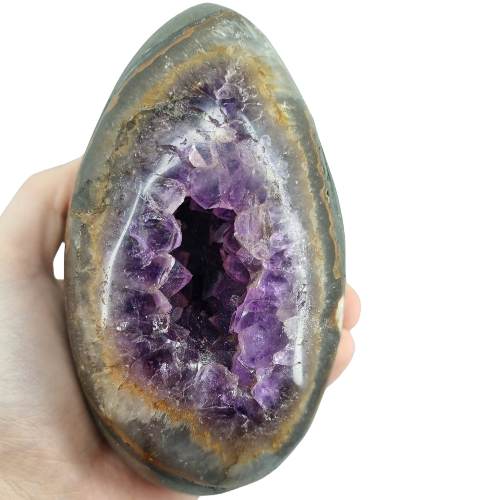 Kindred Crystal Collective — Amethyst Geode Egg, side view of natural amethyst geode egg showing smooth polished exterior and sparkling violet crystal cavity