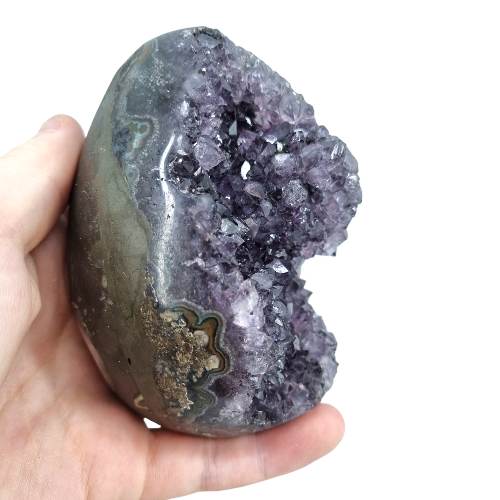 Amethyst druzy cluster egg close-up showing glittering purple crystals within polished exterior, a healing crystal for peace and third eye chakra
