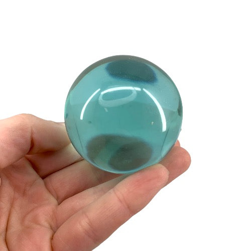 Blue Obsidian Sphere — polished teal volcanic glass sphere, size reference with hand