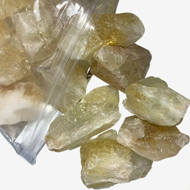 Kindred Crystal Collective — Citrine Rough 1KG Light, pale golden raw citrine chunks spilling from a clear bag on white background.

