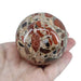 Conglomerate jasper sphere close-up revealing natural mosaic of stone fragments in rich earthy tones, a unique grounding crystal for sacred spaces
