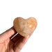 Kindred Crystal Collective — Hematoid Quartz Heart, hand-held polished Fire Quartz crystal heart showing warm peachy-orange tones and natural Hematite patterning, size reference