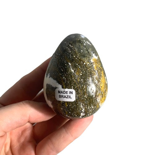 Kindred Crystal Collective — Ocean Jasper Egg, polished green and golden-yellow ocean jasper egg with orbicular spotting, size reference held in hand