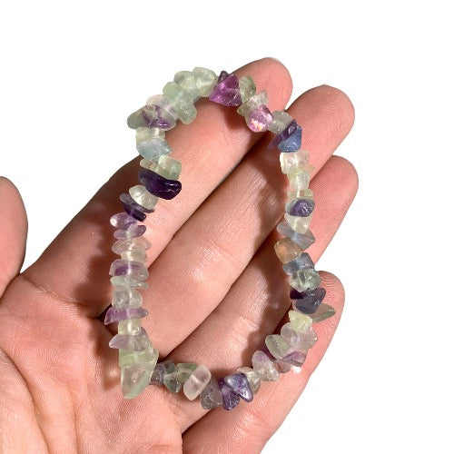 Kindred Crystal Collective — Rainbow Fluorite Chip Bracelets (Pack of 5), five green, purple and translucent chip bracelets arranged around a white crystal display.
