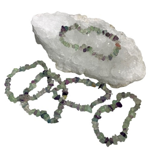 Kindred Crystal Collective — Rainbow Fluorite Chip Bracelets (Pack of 5), five green, purple and translucent chip bracelets arranged around a white crystal display.