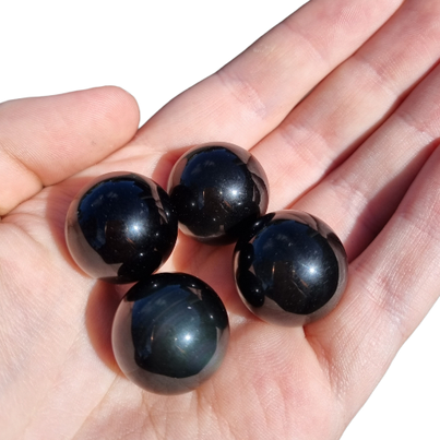 Kindred Crystal Collective — Rainbow Obsidian Mini Sphere Pack, four polished deep black rainbow obsidian mini spheres, size reference held in open palm