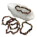 Kindred Crystal Collective — Rhodonite Chip Bracelet (Pack of 5), five mixed pink and dark stone chip bracelets arranged around a white crystal cluster on a white background.