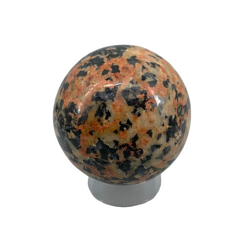 Rhodonite and tourmaline sphere close-up revealing dramatic contrast of vibrant pink and deep black veining, a healing crystal for heart chakra and root chakra balance