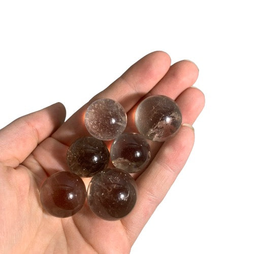 Kindred Crystal Collective — Smoky Quartz Mini Sphere Pack, six polished translucent smoky brown quartz mini spheres, size reference held in open palm