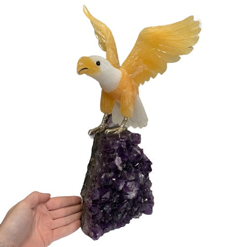 Kindred Crystal Collective — Yellow and White Calcite Eagle, hand-carved crystal eagle on amethyst cluster base, size reference with hand