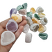 Kindred Crystal Collective — Ema Eggs Mixed 500g, eighteen naturally tumbled river stones held in hand showing a mix of amethyst, rose quartz, clear quartz, green and yellow varieties with frosted exterior and polished window