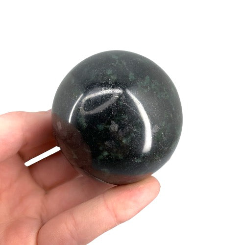 Nephrite jade sphere close-up showing rich green tones and smooth polished surface, a timeless auspicious crystal for feng shui, protection and prosperity